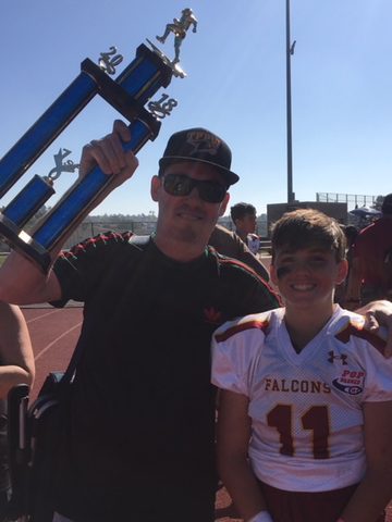 Jason and Ryan with a Pop Warner football trophy, 2018